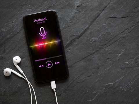 Earphones and mobile phone with podcast app on screen